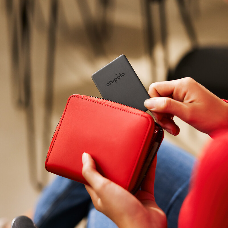 Person legt einen Chipolo-Tracker in eine rote Brieftasche ein